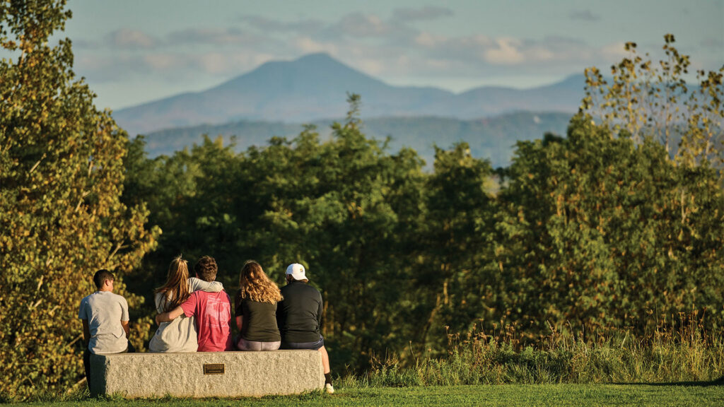 Students sitting on a bench looking at mountains