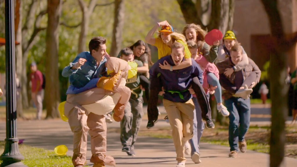 Group of students running on campus doing piggy back